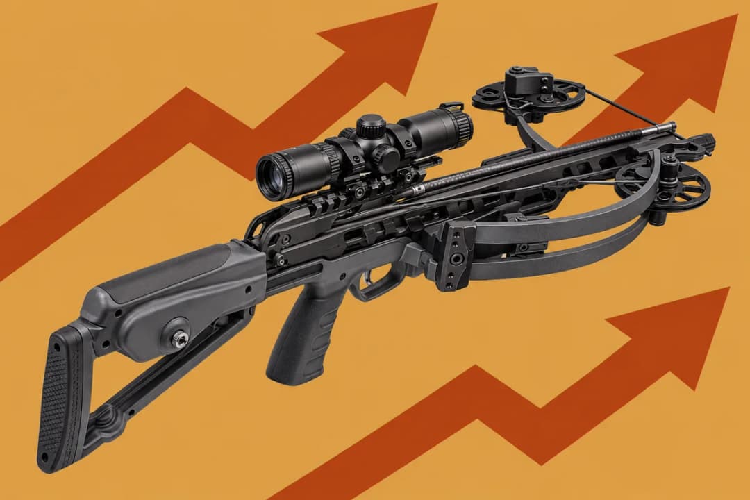 A compact dark grey reverse-draw horizontal bow with a scope, pistol grip and adjustable stock on flat gold, with big rust zigzag arrows rising behind it